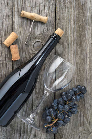 Wine bottle, an empty wine glass, grapes and corkscrew on gray wooden table. Top view.の写真素材