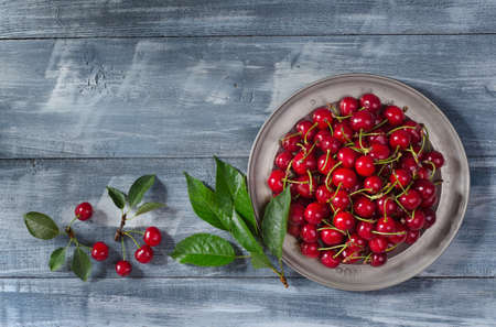 Vintage metal plate with ripe cherries on wooden background with copy space for your text. Top view. Flat lay.の写真素材