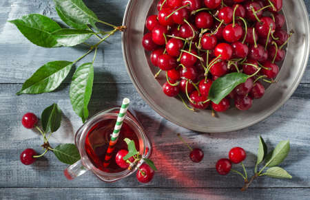 Top view of a glass mason jar with cherry juice and cherry berries in a metal plate.の写真素材