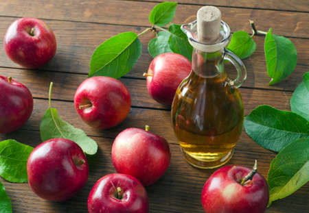 Ripe apples and apple cider vinegar in glass bottle on wooden table. Top view.の写真素材