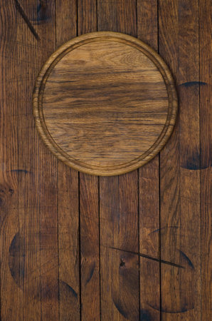 Round kitchen pizza board on old wood table in rustic style with copy space for your text. Top view.の写真素材