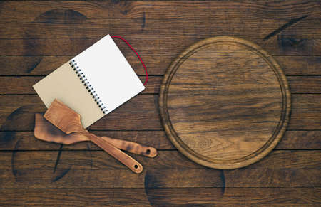 Round kitchen board and notepad for the menu on the old wooden table in rustic style. Top view.の写真素材