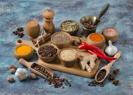 Spices for Indian cuisine. Salt, pepper, ginger, chili, coriander, turmeric and other on colorful blue background.の写真素材