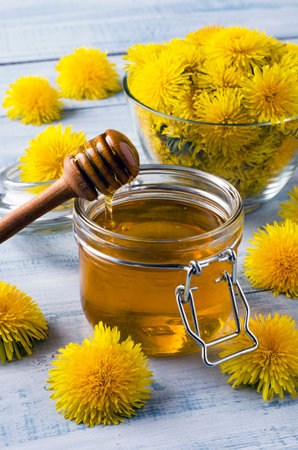 Jar with homemade honey of dandelion's flowers on light blue wooden table. Close-up.の写真素材