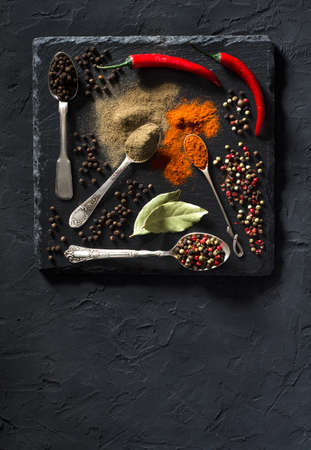 Top view on colorful various spices in vintage metal spoons on black textured background with space for your text. Food art.の写真素材