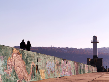 VARNA - 18 November: People walk near the lighthouse at the seaport of Varna, graffiti on a concrete wall. November 18, 2015 in Varna, Bulgariaのeditorial素材