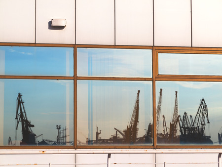 Silhouette of marine cranes in the backlight is reflected in the windows of Seaportのeditorial素材
