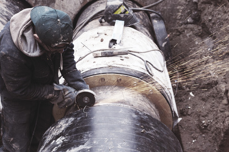 Odessa, Ukraine - October 11, 2016: Repair of heating duct. The workers, welders made by electric welding and gas welding on large iron pipes at a depth of excavated trench.のeditorial素材