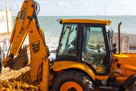 ODESSA, UKRAINE -17 October 2016: Excavator digs sand on a sea beach. Wheel loader excavator doing excavation work for the construction of urban development on the beach.のeditorial素材