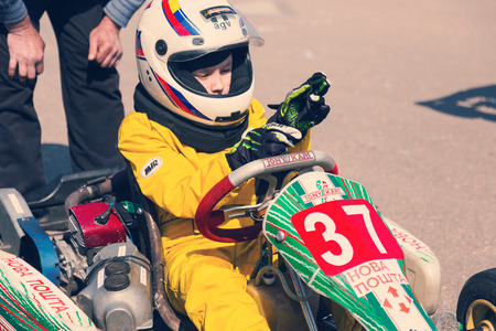 ODESSA, UKRAINE - APRIL 2, 2017: Competitions on the picture, pilots in helmet and in racing clothes participate in the card race. Carting show. Children and adult racers on bright branded maps.のeditorial素材