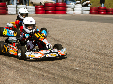 ODESSA, UKRAINE - APRIL 2, 2017: Competitions on the picture, pilots in helmet and in racing clothes participate in the card race. Carting show. Children and adult racers on bright branded maps.のeditorial素材