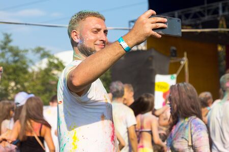 ODESSA, UKRAINE - August 5, 2017: Young people, boys and girls have fun doing selfie during festival of Holi by throwing coloured powder at each other. Festival of Colored Paint, of colors love. Color festのeditorial素材