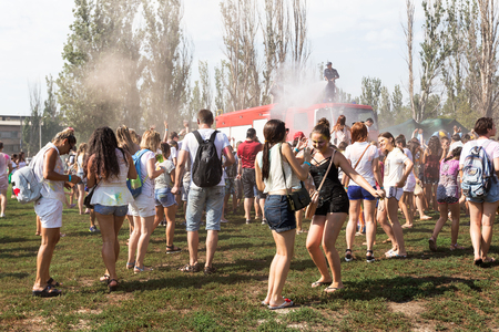 ODESSA, UKRAINE - August 5, 2017: Boys and girls in wet clothes fun to do selfie during festival of Holi. Smiling fireman sitting on fire truck pours water on people from brandsby. Festival Color festのeditorial素材