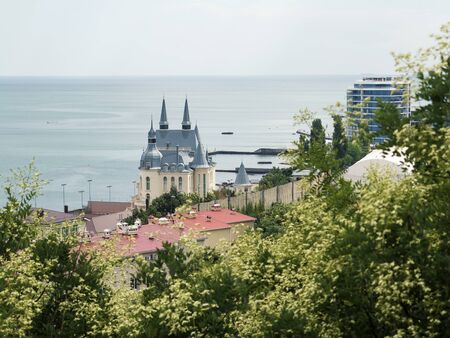 Odessa, Ukraine - July 16, 2018: panoramic view of the sea and houses, through the green crown of...