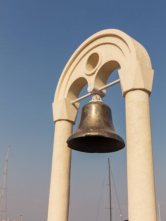 Bronze bell in the rays of the setting sun against a cloudless sky in the port of Odessaのeditorial素材