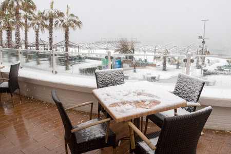 Belek, Antalya, Turkey - January 26, 2022: Heavy snowfall on the Mediterranean coast. Snow storm and white covered palm trees. Empty beaches and hotel cafes.のeditorial素材