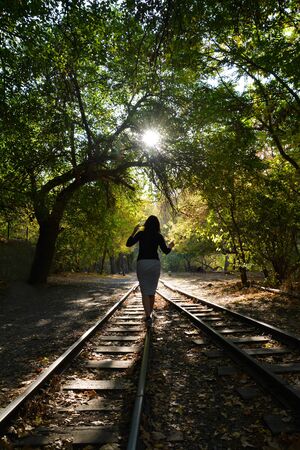 Beautiful girl walking on railway road in forest