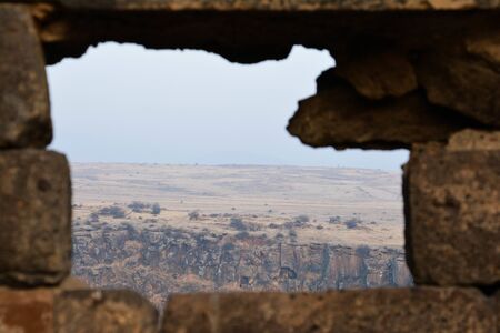 A stone window looks directly into the mountainsの写真素材