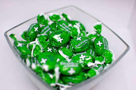 Mint candies in a vase. Mint candies in green packaging. Candy isolated on green. Candy in a vase.