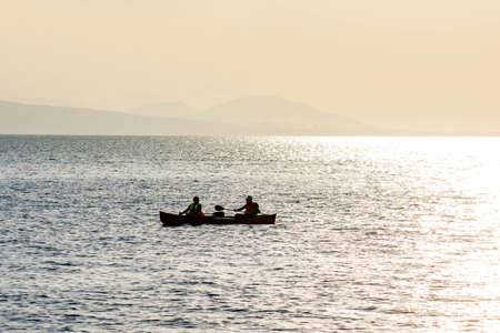 Two on a boat row on the waves of the sea. Two athletes went to sea on a boatの写真素材