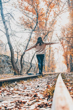 Golden autumn forest and a girl. A girl walks on a train rail in the forestの写真素材