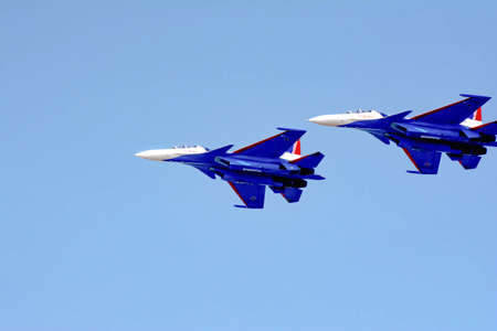 Aviation pilots demonstrate high aerobatics on fighters. Aircraft bombers in the blue sky. Military...