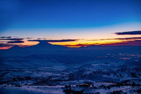City lights. Beautiful landscape with glowing city houses, mountains and fantastic sunsetの写真素材