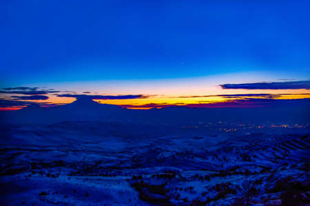 City lights. Beautiful landscape with glowing city houses, mountains and fantastic sunsetの写真素材