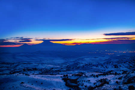 Silhouettes of the mountains in the silence of the night. Sunset and beautiful Mount Ararat. The sky turned orange and blueの写真素材