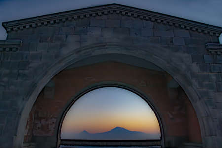 Mountain and arch. The mountain and sunset are visible through the arch. The sun is setting over the mountainの写真素材