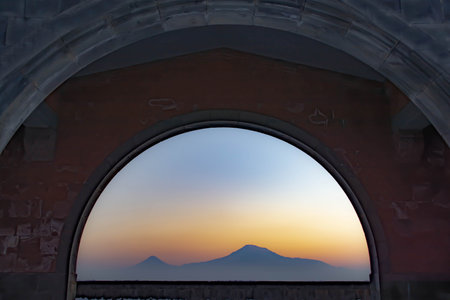 Mountain and arch. The mountain and sunset are visible through the arch. The sun is setting over the mountainの写真素材