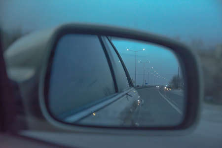 The side window of the car and the movement of cars and street paws are visible in it