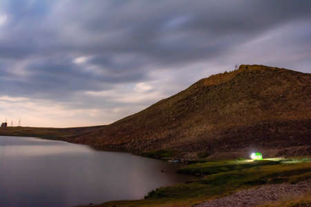 Tent on the shore of the lake. Mountain lake and tent tourists. Small hill and lake. Camping in the mountainsの写真素材