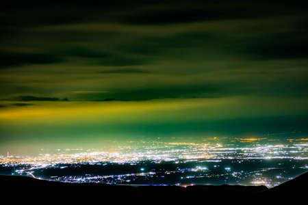 Night city and beautiful sky. Multi-colored clouds on the night city. City lights at nightの写真素材