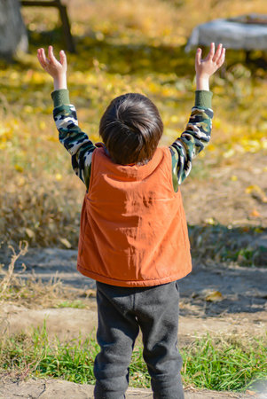The boy looks up and greets the flying planeの写真素材