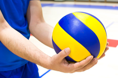 Volleyball player in blue and yellow sportswear holding ballの写真素材
