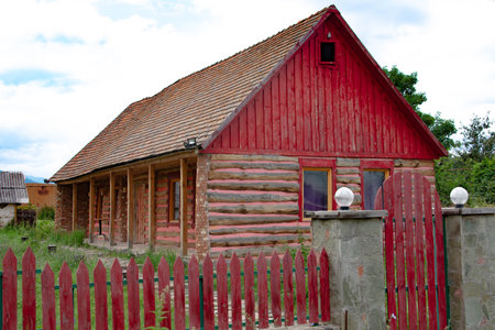 Wooden house with red roof and wooden fence in the village.の写真素材
