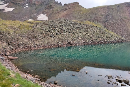Small lake on top of a mountain. Crystal clear lake and mountain. Beautiful landscape with lake, fields and mountainの写真素材