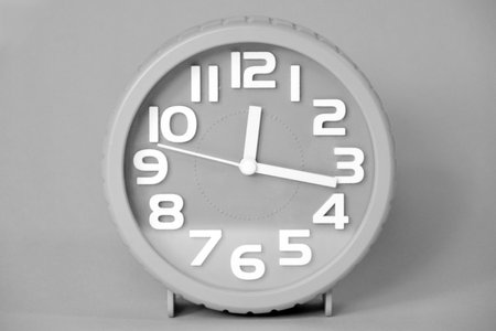 White alarm clock on a gray background. Black and white photo.