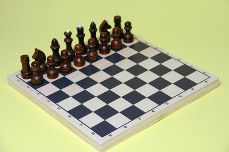 Chess pieces on a chessboard, close-up, on a yellow backgroundの写真素材