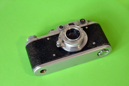 Old camera on a green background, close-up, selective focus