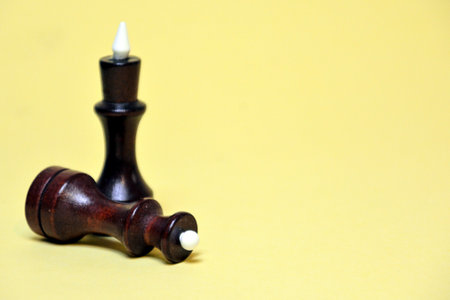 Wooden chess pieces on a yellow background. Selective focus.の写真素材