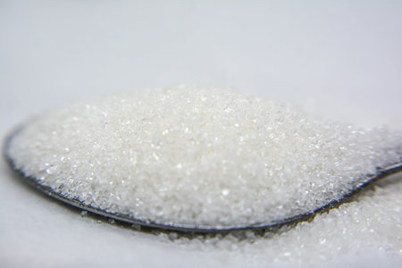 Close up of sugar in spoon on white background. Selective focus.の写真素材