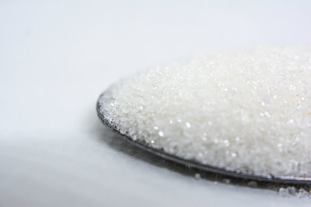 Close up of sugar on spoon isolated on white background. Selective focus.の写真素材