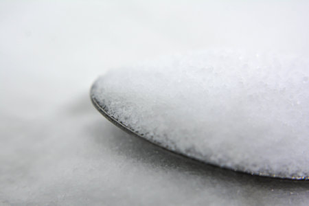 Close up of a spoon full of sugar on a white background.の写真素材