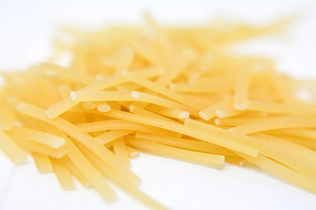 closeup of a pile of uncooked italian pasta on white backgroundの写真素材
