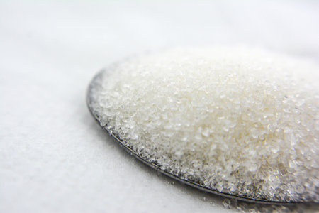 sugar in a spoon on a white background, close-up