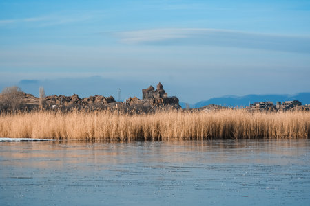 Frozen lake with reeds and old monastery in the background.の写真素材