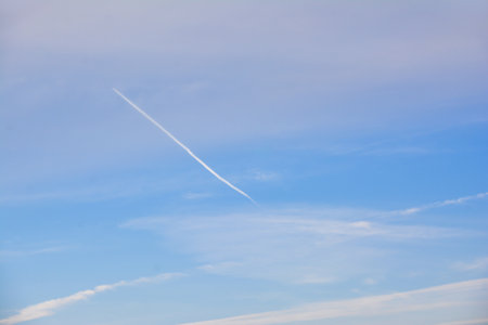 Blue sky with white clouds and contrail, closeup of photo