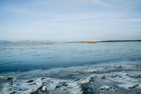 Landscape with frozen lake and mountains on the horizon in winter.の写真素材